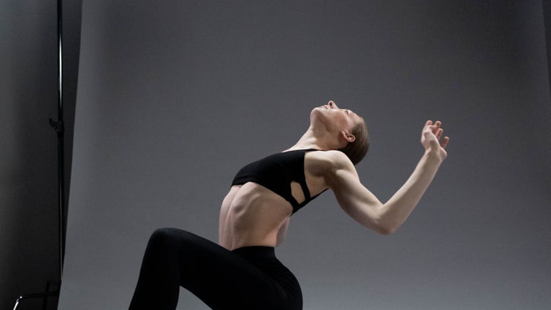 Athletic woman practicing slow movements in a dark studio.